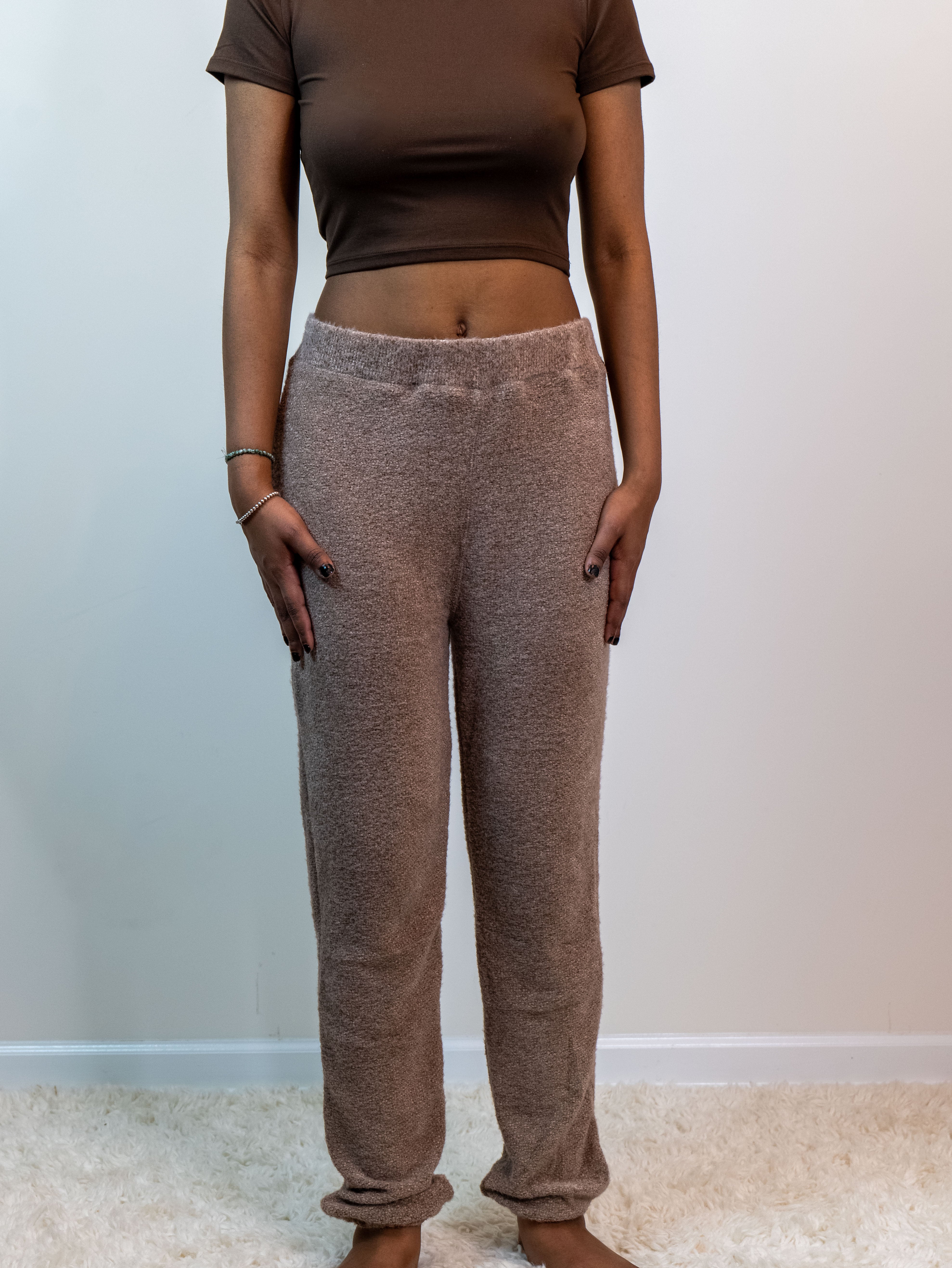 Cocoa-colored fuzzy lounge pants with an elastic waistband and ankle cuffs, made from a plush 60% polyester, 40% nylon blend for cozy comfort. Model is 5'4" wearing a small.