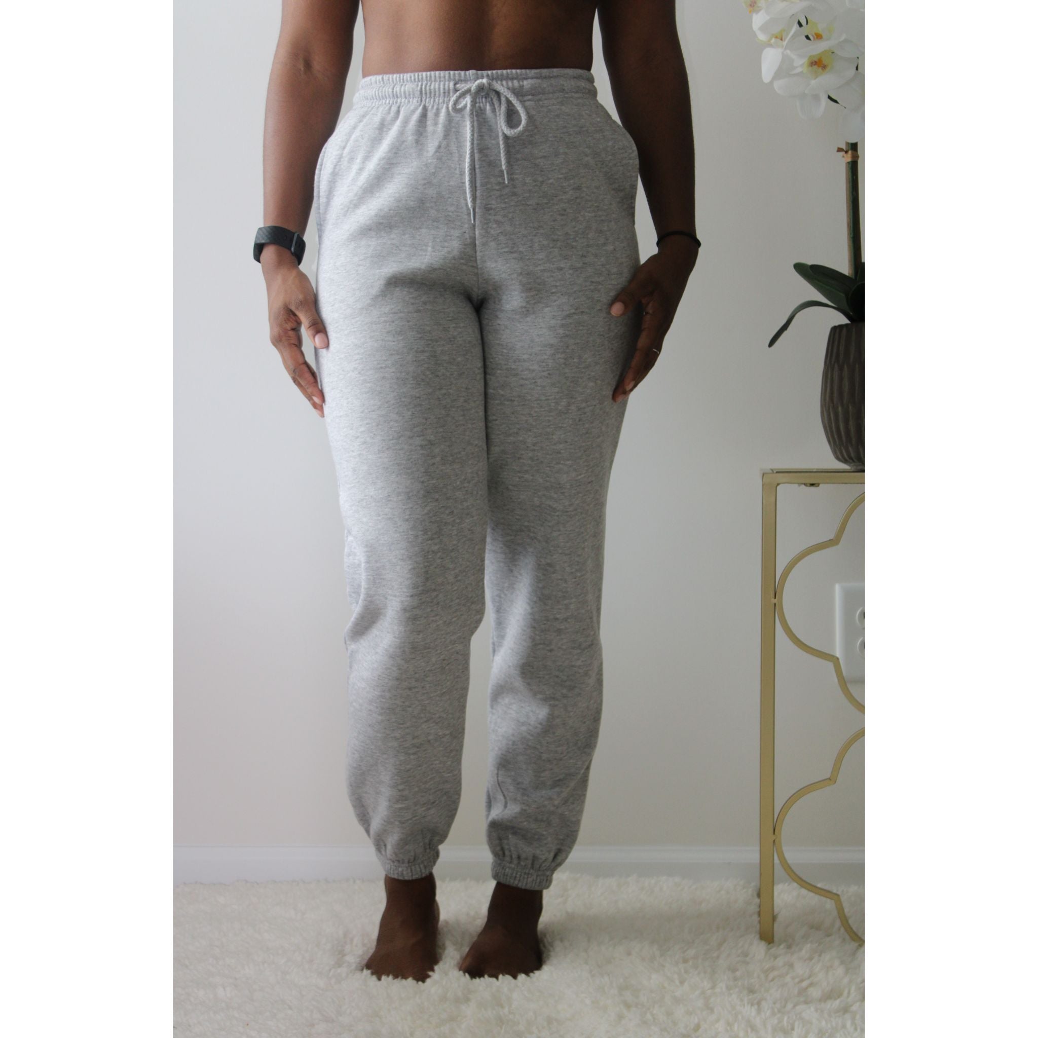 Heather grey sweatpants with side pockets, 2-inch elastic waistband, and elastic cuffs at the ankles, made from 60% cotton and 40% polyester for a comfortable, casual look. Model is 5'4" wearing a small. Front view