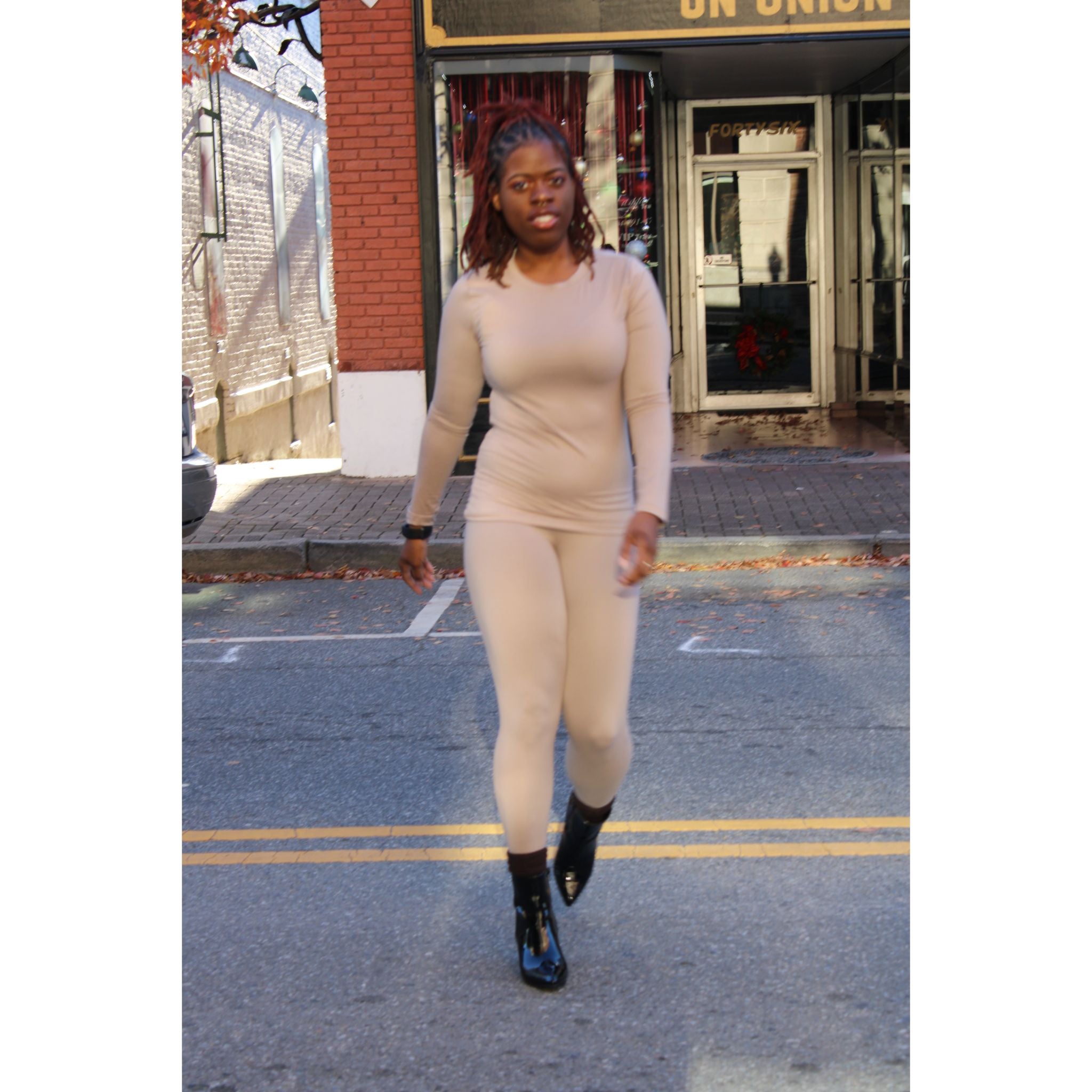 Mocha two-piece lounge set with a fitted long-sleeve top and high-waisted leggings, featuring a snug fit and soft stretch fabric for a cozy, stylish look. Model is crossing the street