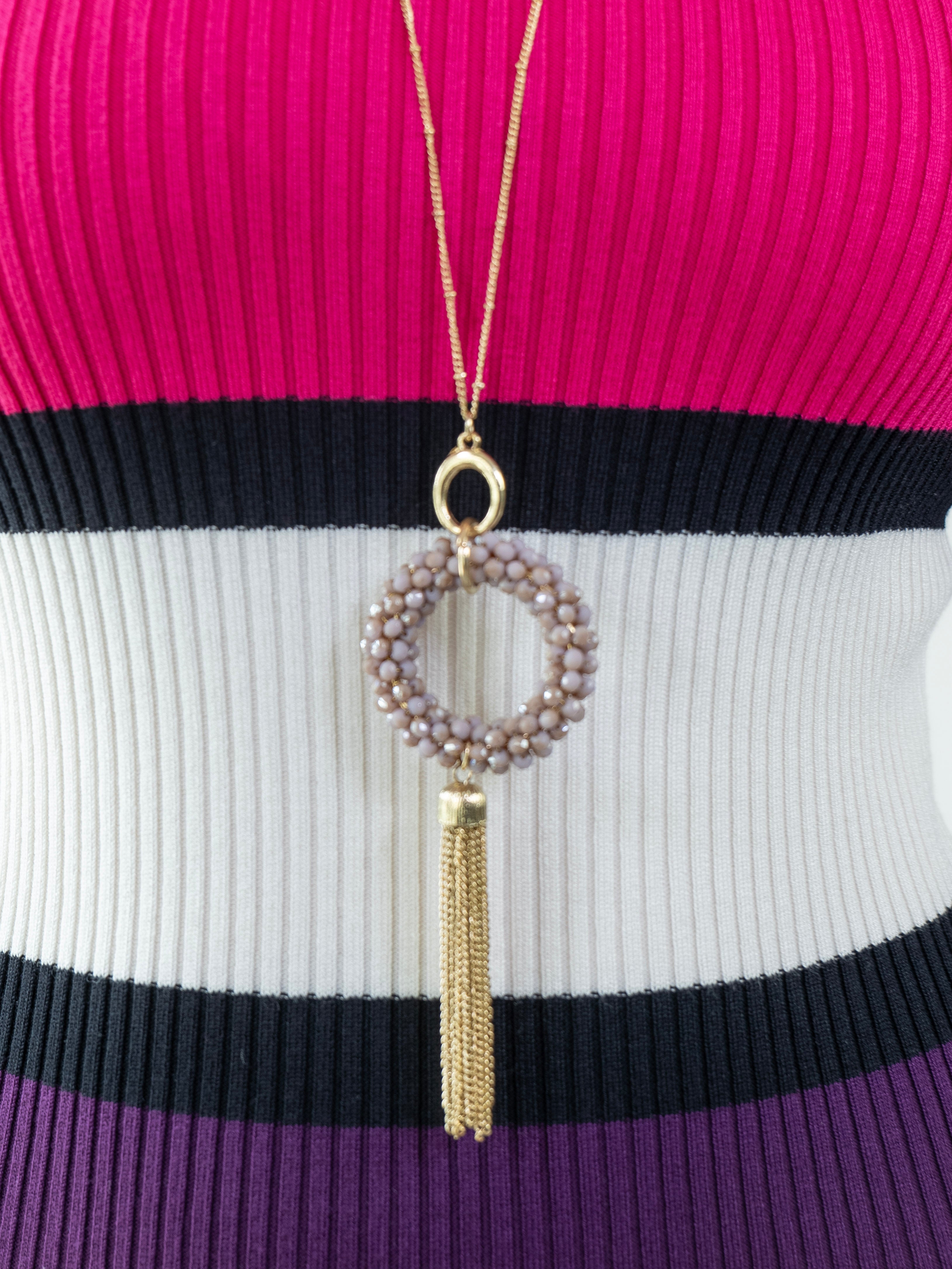 Close-up of upper bodice of the multicolor sweater dress paired with a long gold pendant necklace