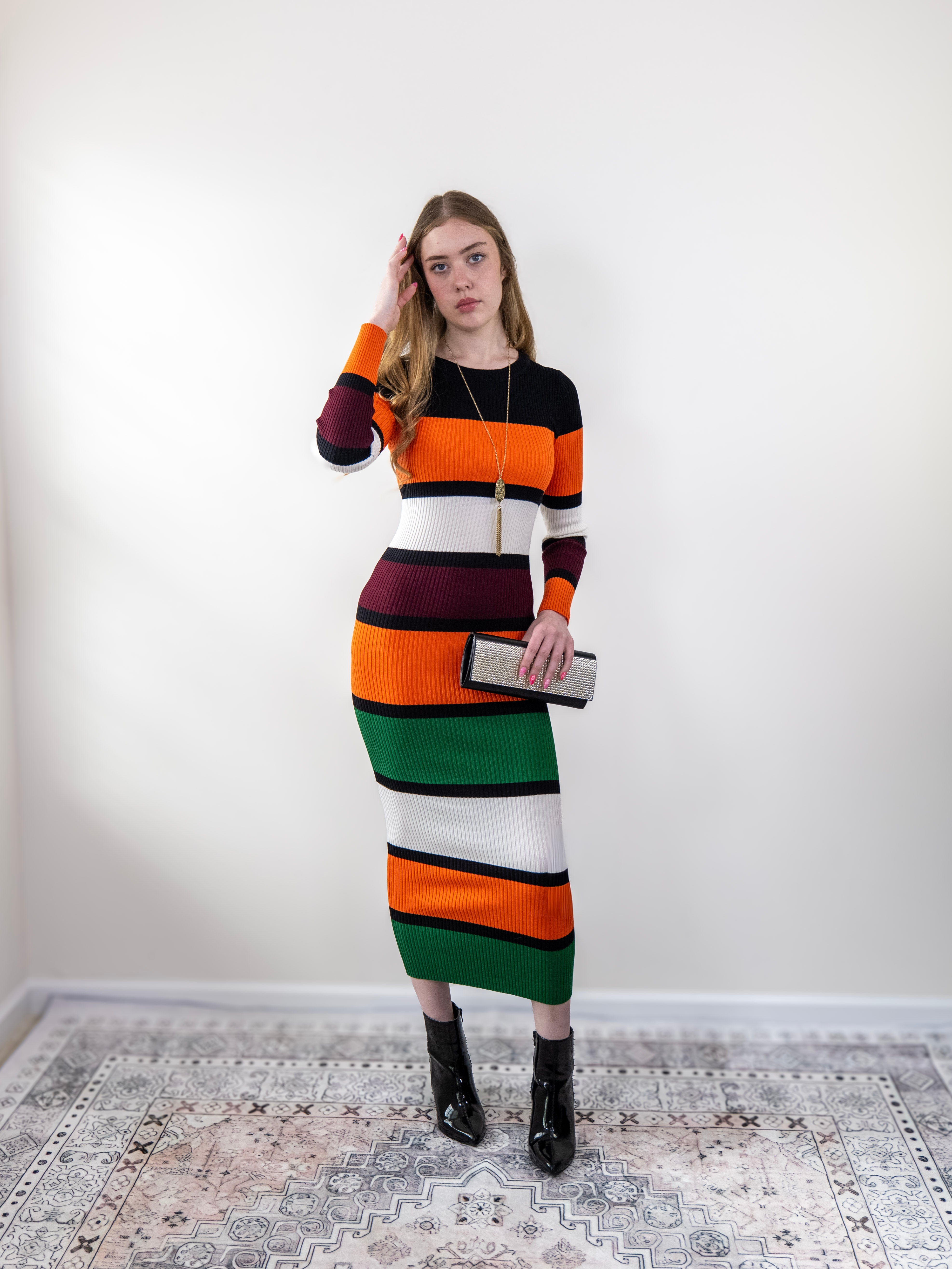 Model wearing orange multi-stripe rib-knit midi sweater dress, standing front view.