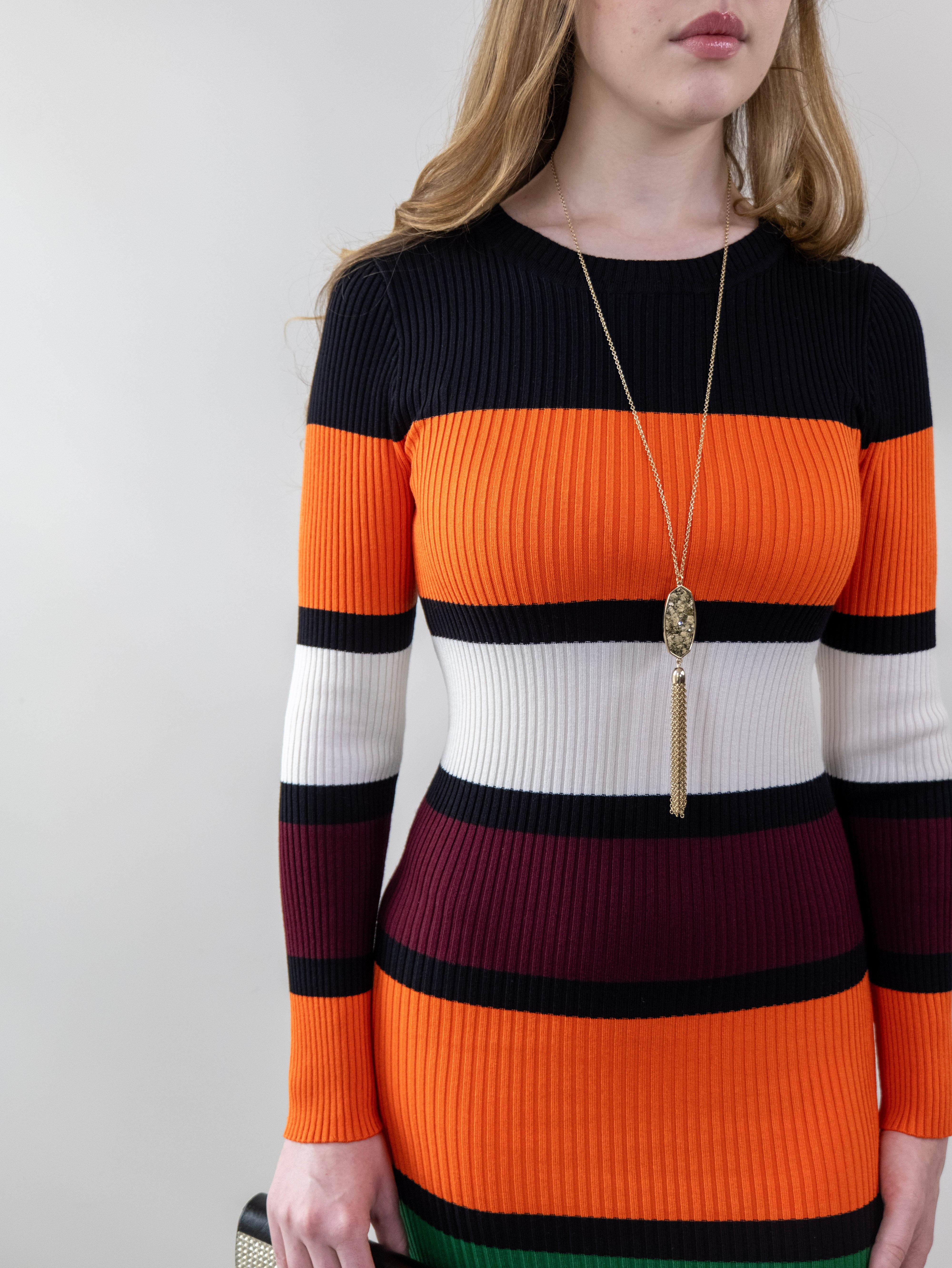 Model wearing orange and burgundy striped rib-knit dress, front mid-frame shot.