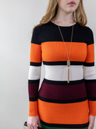 Model wearing orange and burgundy striped rib-knit dress, front mid-frame shot.