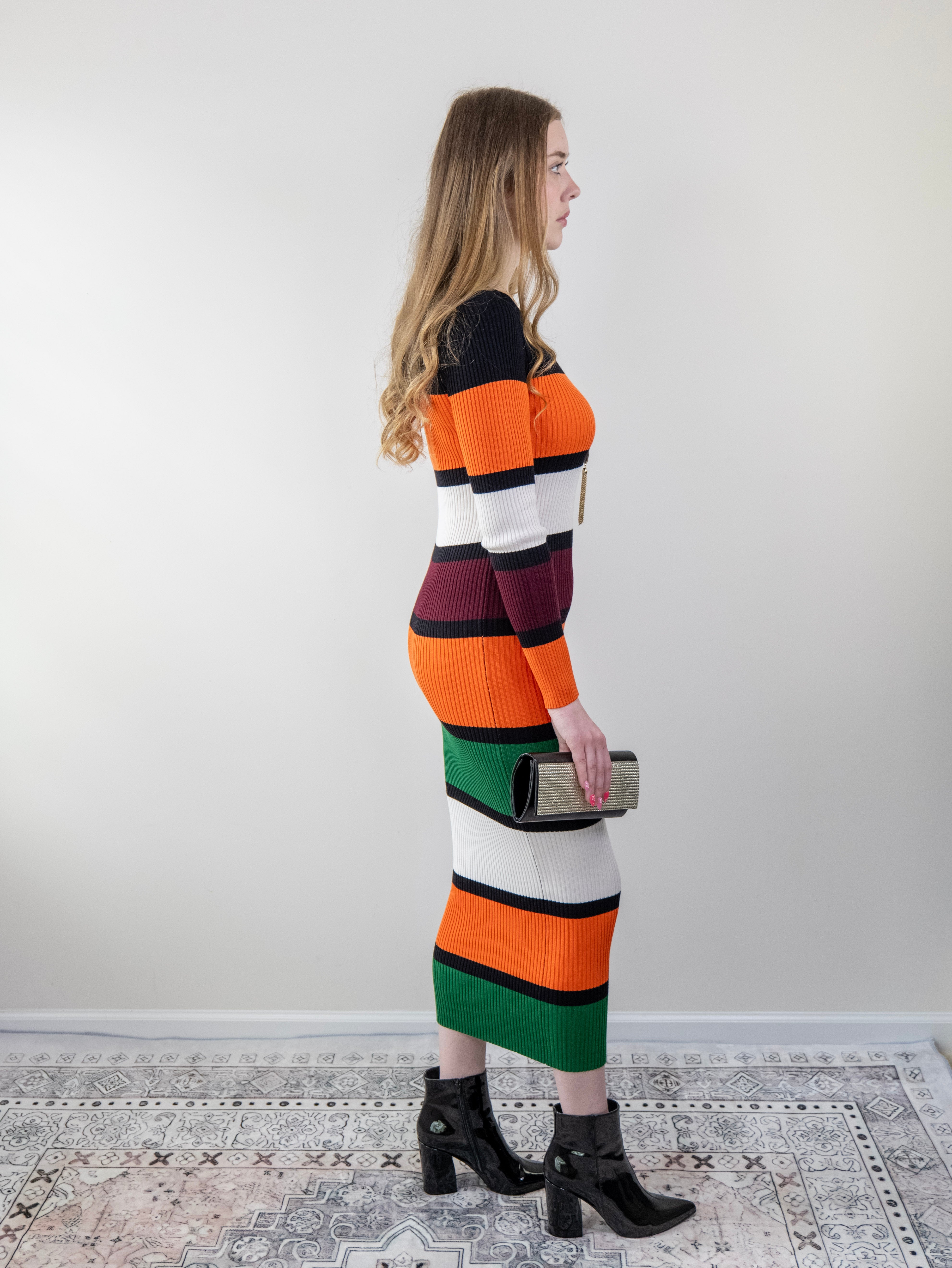 Side view of model wearing orange colour-block rib-knit midi sweater dress.