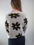 Back view of daisy-print beige sweater on model.