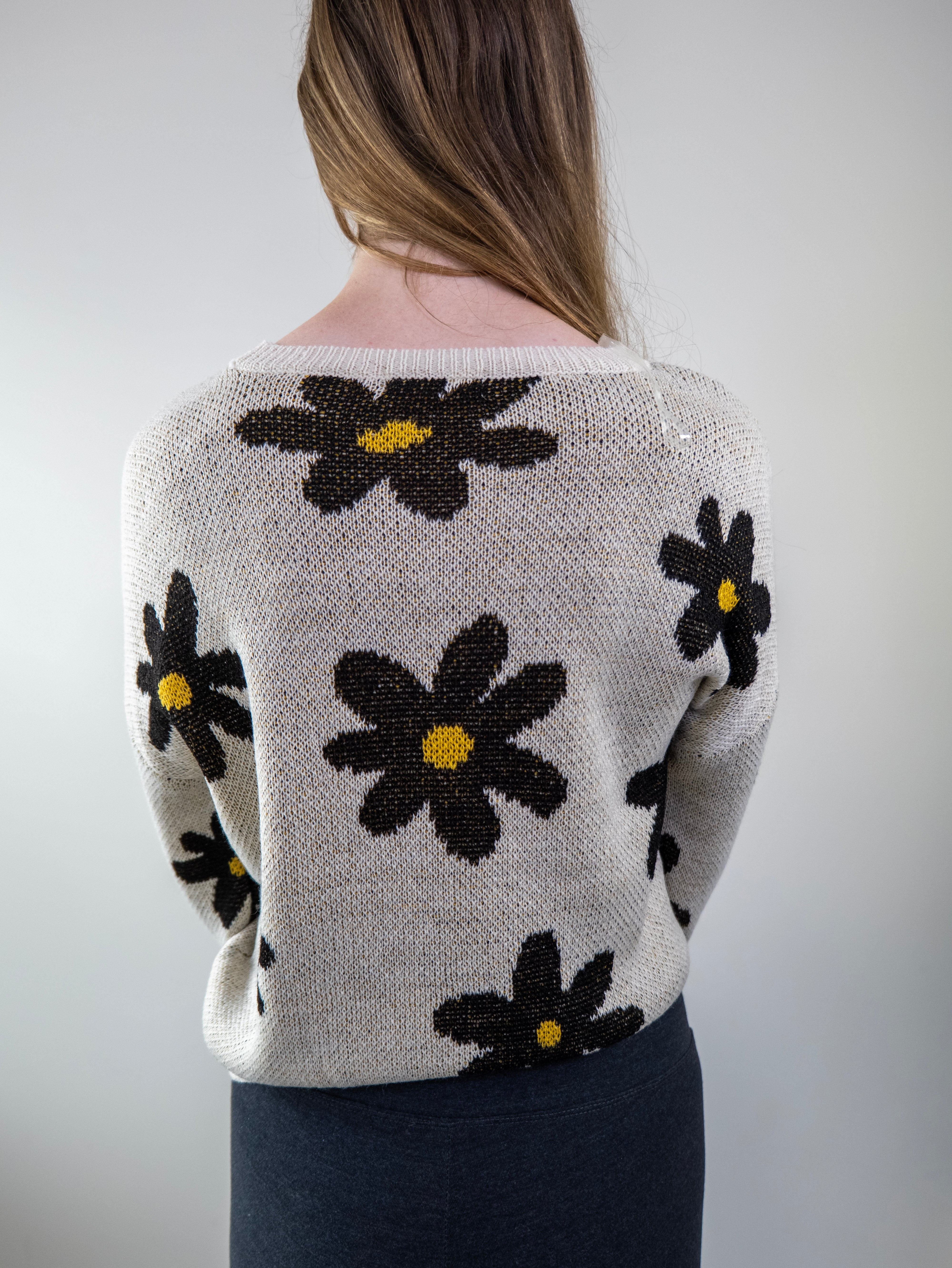 Back view of daisy-print beige sweater on model.