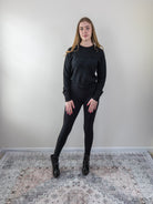 Model wearing a black “Bonjour” long-sleeve knit sweater, standing front-facing