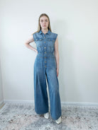 Model wearing a loose-fit blue denim jumpsuit, full-length front view.
