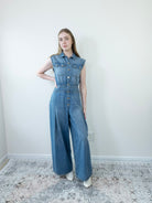 Model walking in loose-fit denim jumpsuit, relaxed wide-leg style.
