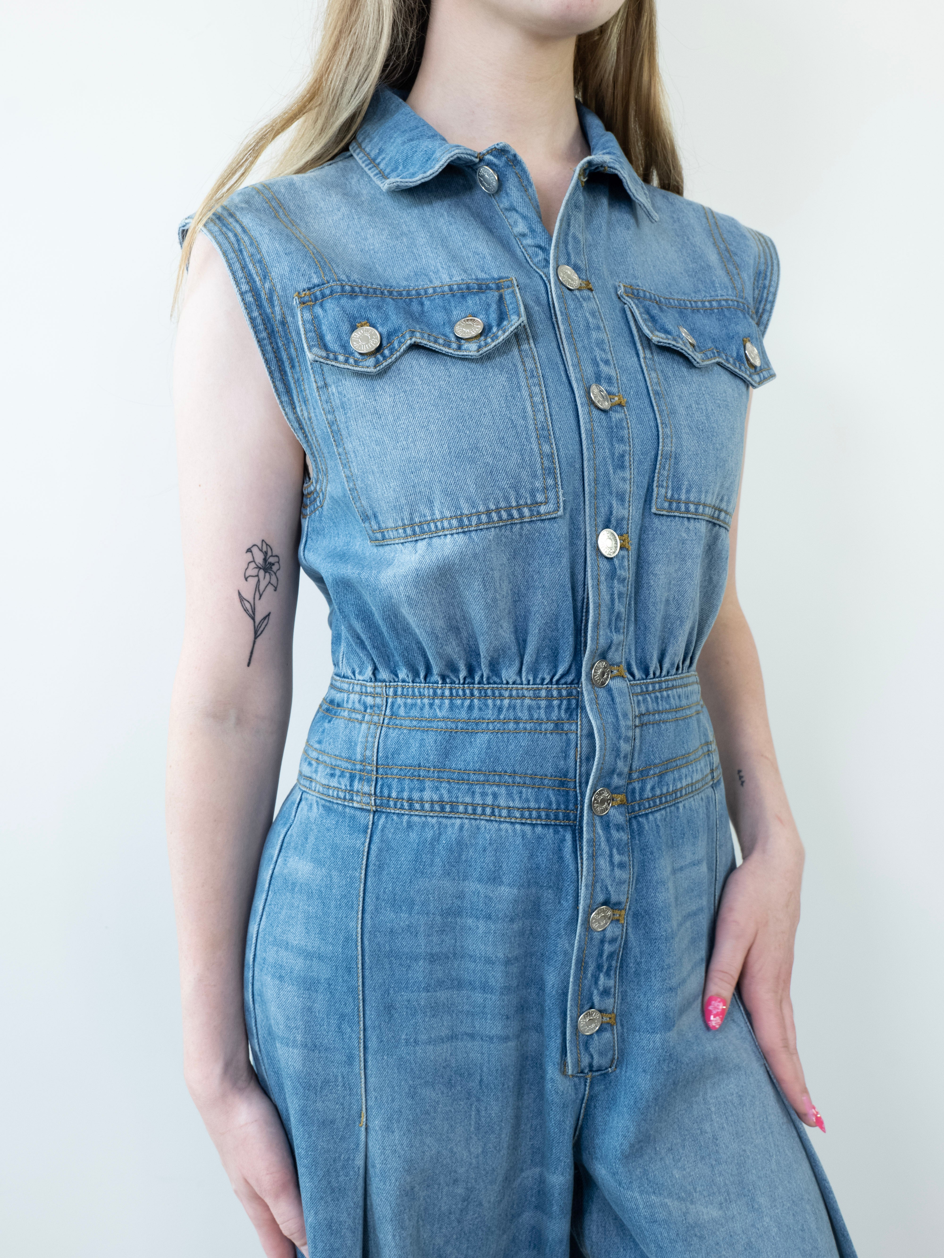 Close-up of button-down chest detail on denim jumpsuit.
