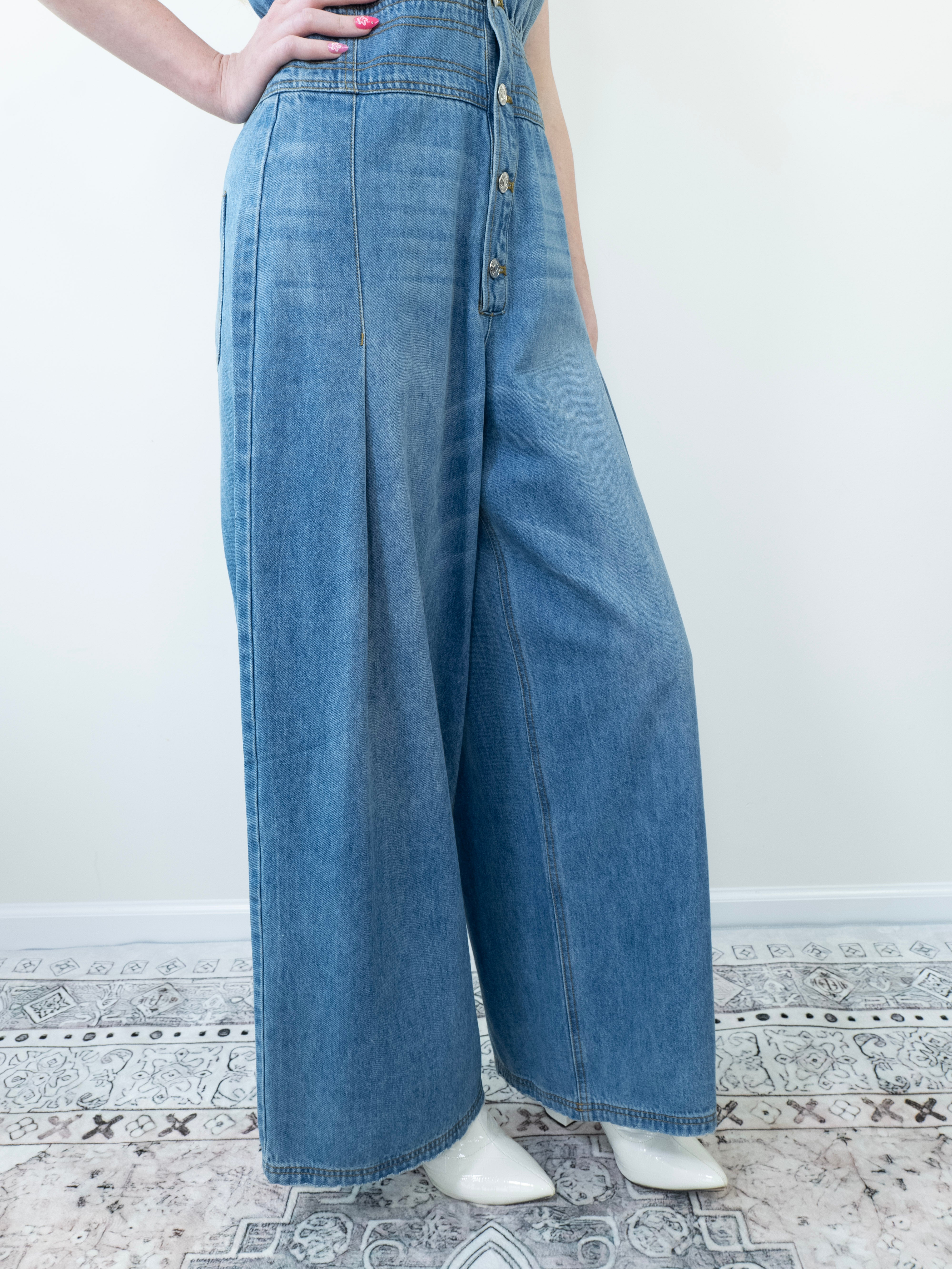 Close-up of lightly distressed hem on wide-leg denim jumpsuit.
