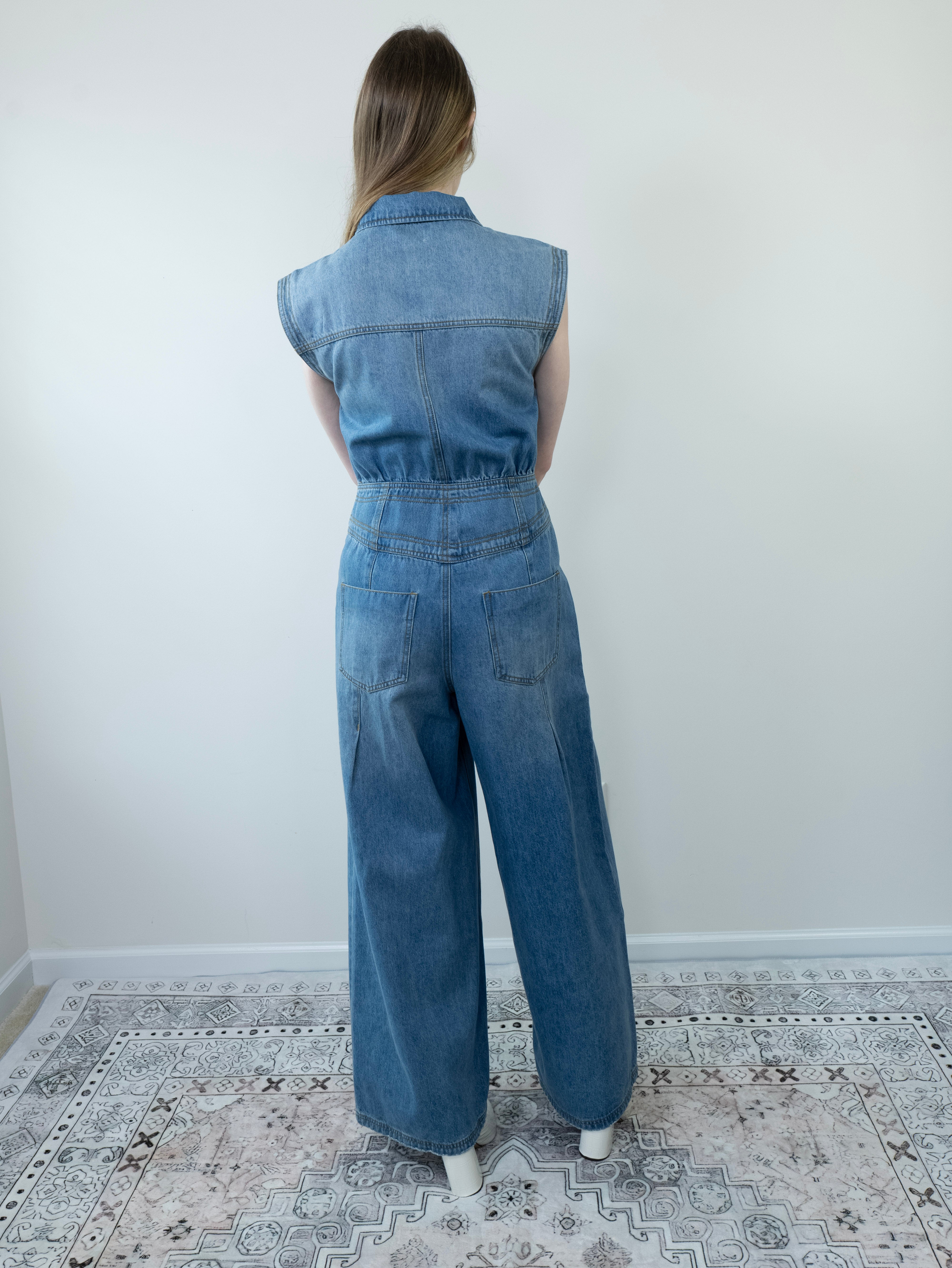 Back view of denim jumpsuit with tailored seams and pockets.

