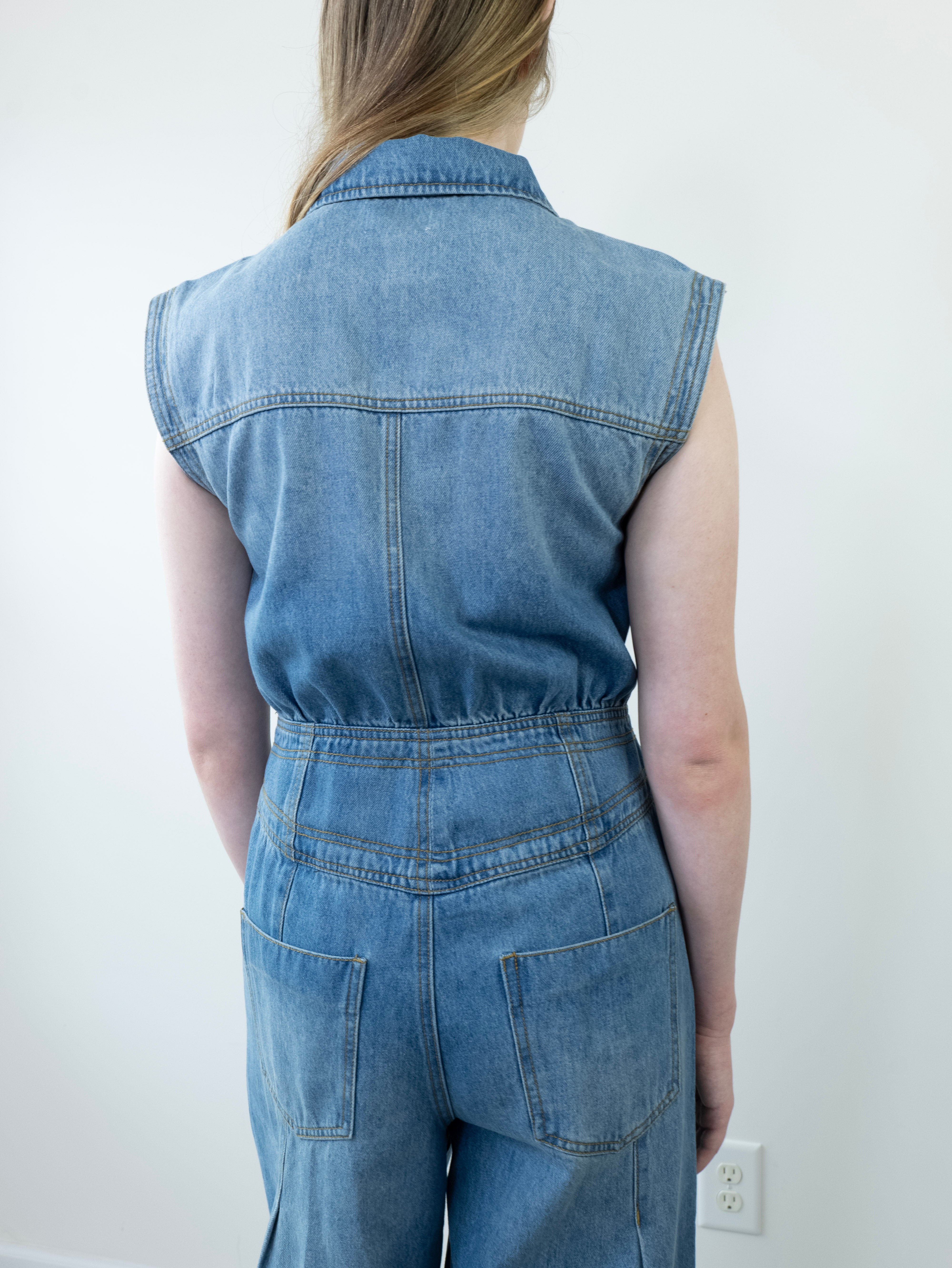 Back view of denim jumpsuit with tailored seams and pockets.
