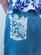 Close-up of white crochet lace panel on the side of the denim maxi skirt.