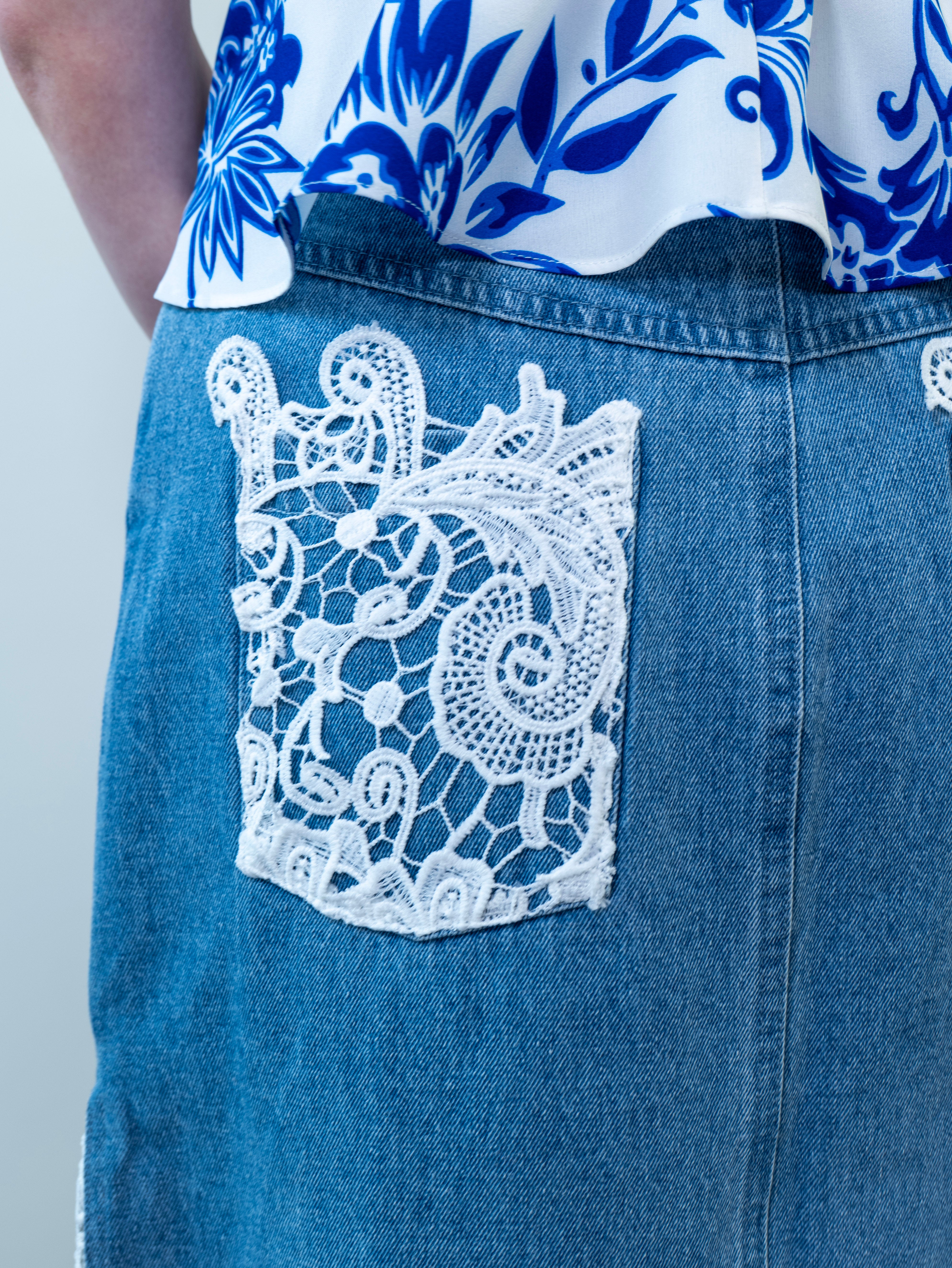 Close-up of white crochet lace panel on the side of the denim maxi skirt.