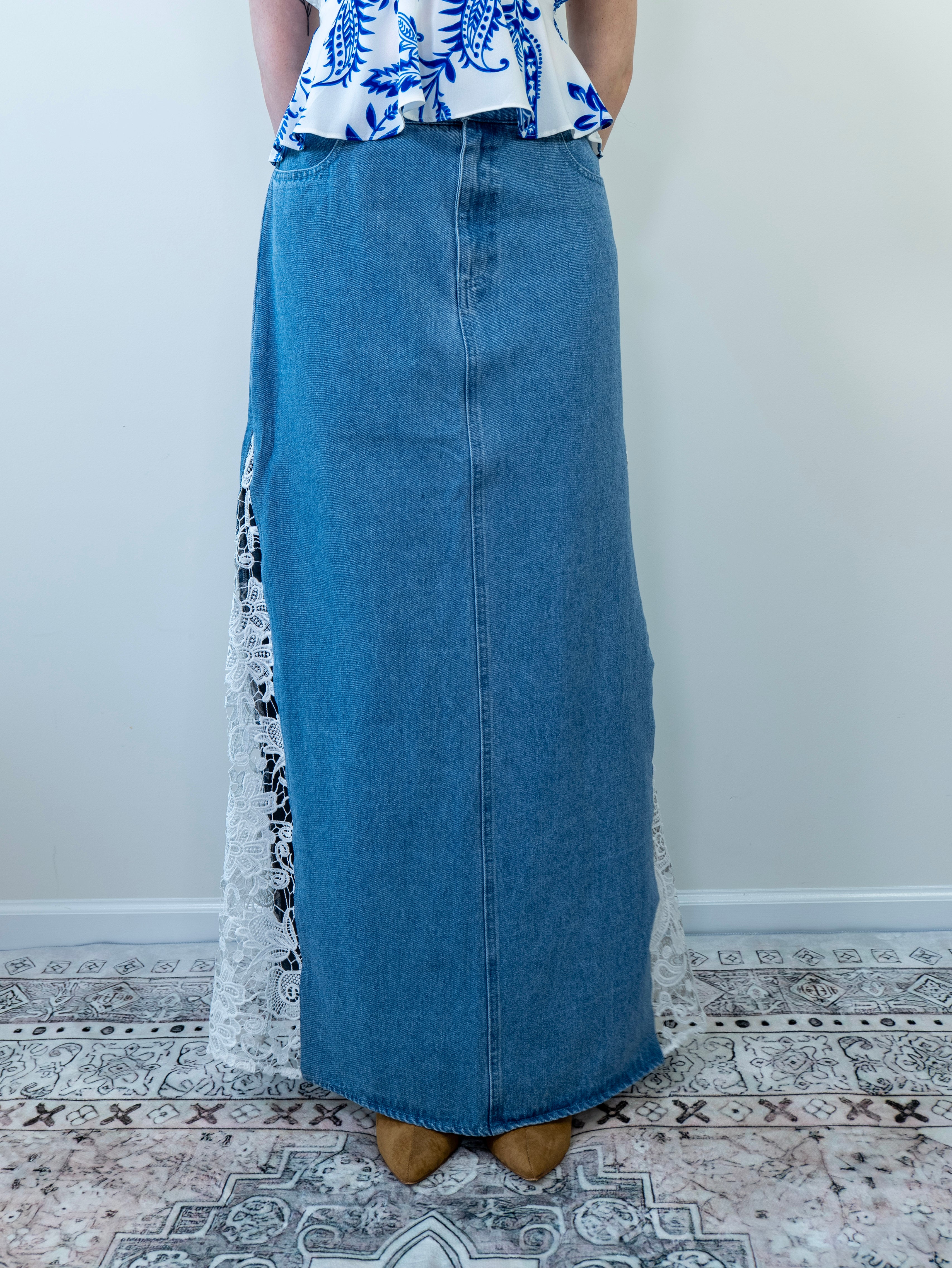 Model wearing a denim blue maxi skirt with crochet lace side panels, standing against a light background.