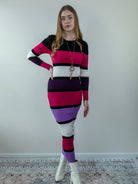 Model posing in a color-block midi sweater dress with long sleeves, showing front angle.