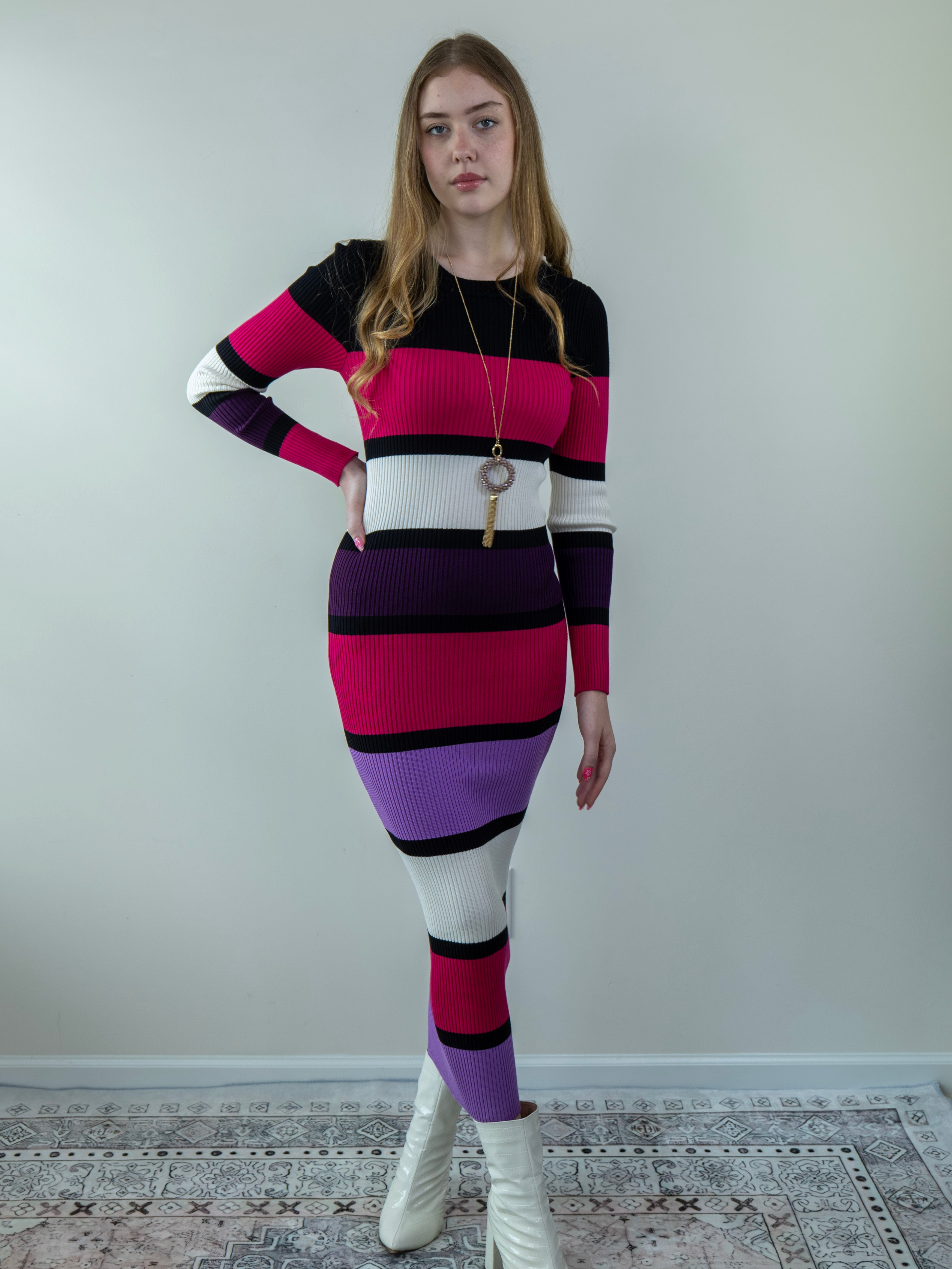 Model posing in a color-block midi sweater dress with long sleeves, showing front angle.