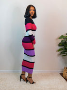 Long bodycon sweater dress with a color block design in magenta, black, off-white, light purple, and burgundy; ribbed material with long sleeves and a round neckline.
