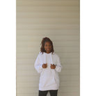 White oversized hoodie with thick drawstring, kangaroo pocket, and long sleeves, made for a cozy and relaxed fit. Model showing the front holding the drawstring.